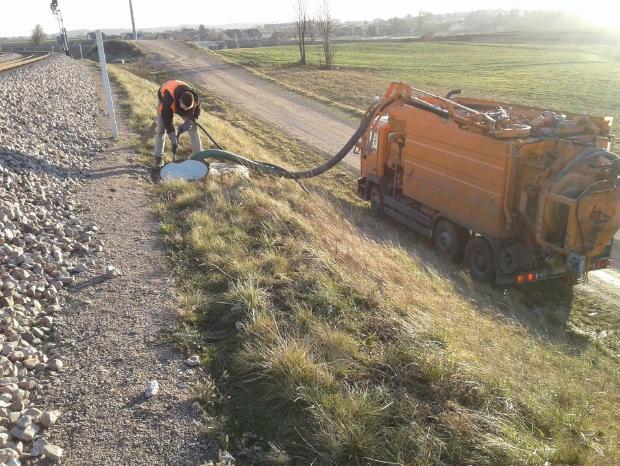 Pracownik z rurą przy studzience